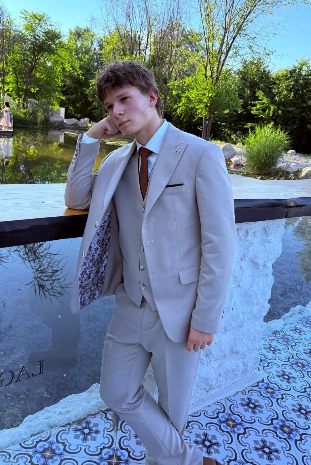 Octavian Rotaru in a beige suit, leaning on a stone ledge with his hand on his chin